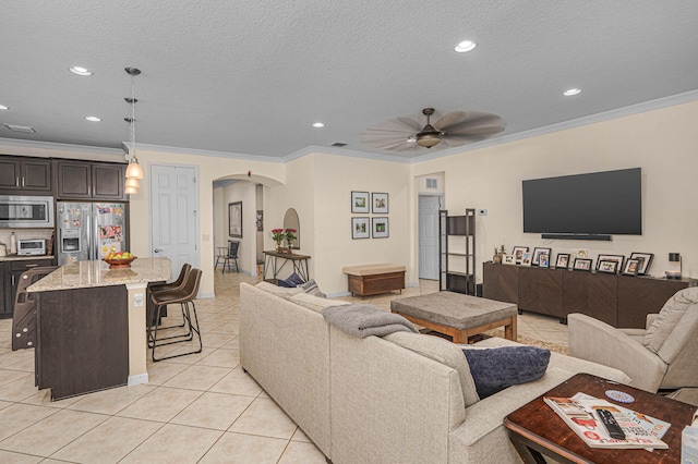 living area featuring crown molding, a ceiling fan, recessed lighting, arched walkways, and light tile patterned floors