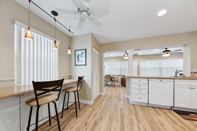 kitchen featuring dishwasher, hanging light fixtures, light wood-type flooring, white cabinetry, and a sink