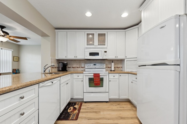 kitchen with white appliances, a sink, white cabinetry, and decorative backsplash