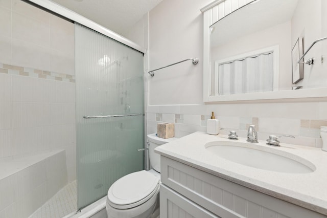 bathroom with toilet, a stall shower, vanity, and tile walls