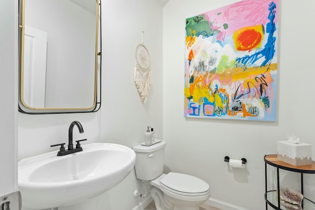 bathroom featuring a sink, baseboards, and toilet