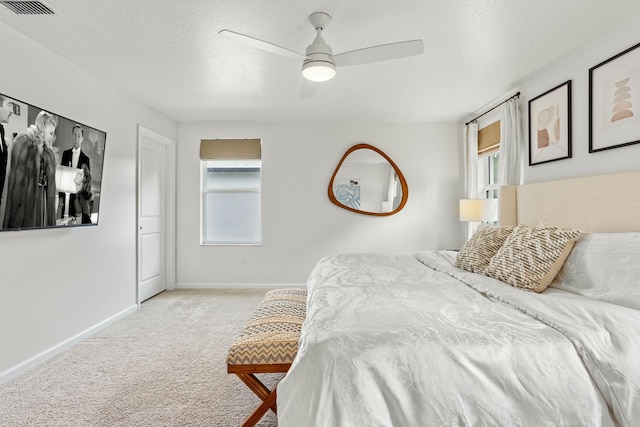 bedroom featuring multiple windows, light colored carpet, baseboards, and a textured ceiling