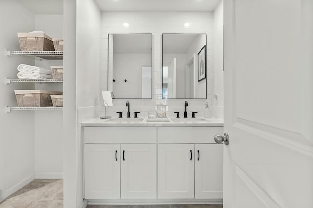 full bath with a sink, baseboards, and double vanity