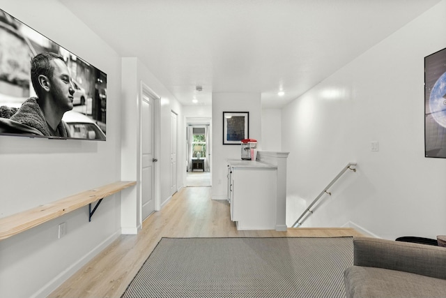 hallway featuring an upstairs landing, light wood-style flooring, and baseboards