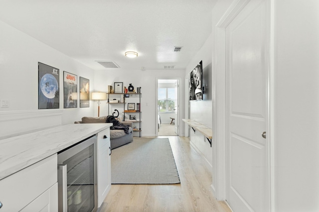 office featuring light wood-type flooring, visible vents, a bar, and beverage cooler