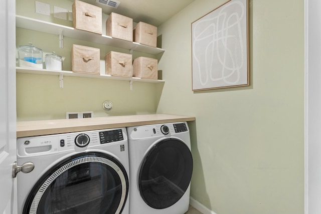 clothes washing area with laundry area, visible vents, and washer and clothes dryer