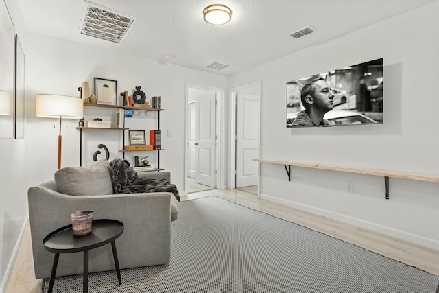 living room featuring wood finished floors, visible vents, and baseboards