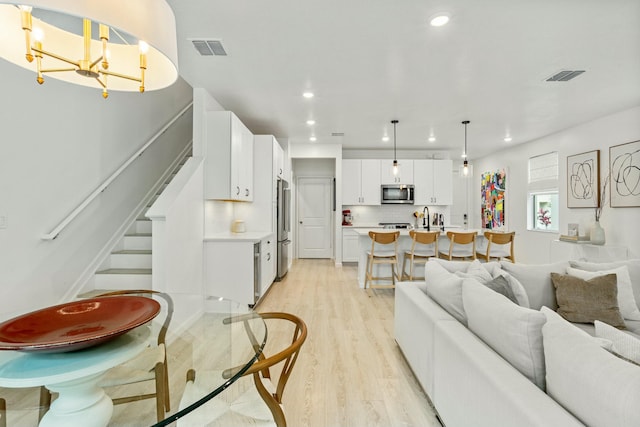 living room with stairway, recessed lighting, visible vents, and light wood finished floors