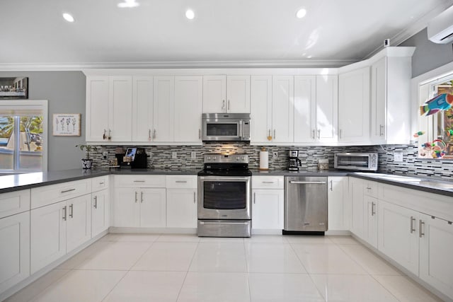 kitchen featuring light tile patterned floors, tasteful backsplash, dark countertops, appliances with stainless steel finishes, and crown molding