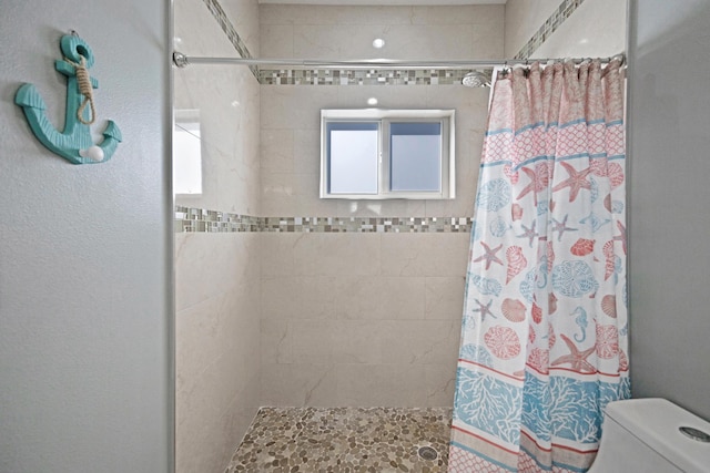 bathroom featuring tiled shower and toilet