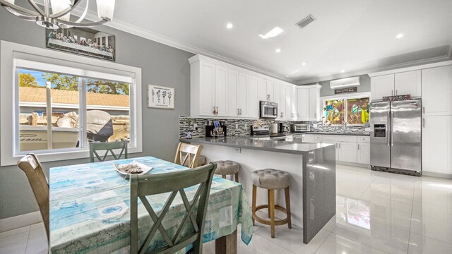 kitchen featuring stainless steel appliances, a peninsula, visible vents, ornamental molding, and tasteful backsplash