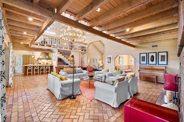 living area featuring wood ceiling, wooden walls, an inviting chandelier, and stairs