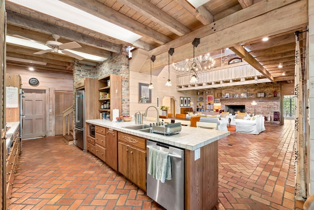 kitchen with appliances with stainless steel finishes, brown cabinetry, brick floor, and a peninsula