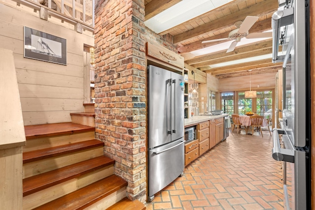 kitchen with brick floor, wooden walls, stainless steel appliances, and beamed ceiling