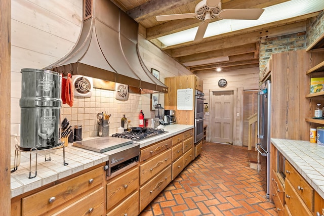 kitchen featuring tasteful backsplash, brown cabinetry, tile countertops, and open shelves