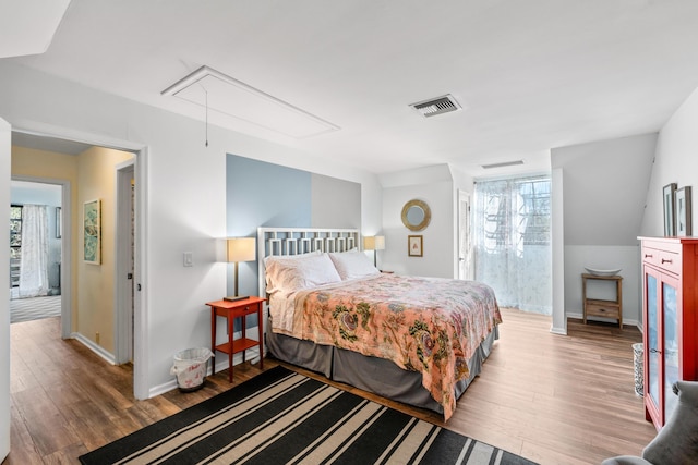 bedroom featuring attic access, multiple windows, visible vents, and wood finished floors