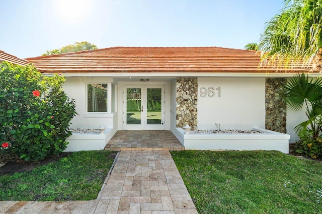 view of exterior entry featuring stone siding, french doors, and stucco siding