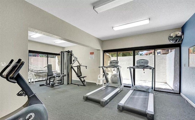 workout area with plenty of natural light, a textured ceiling, and baseboards