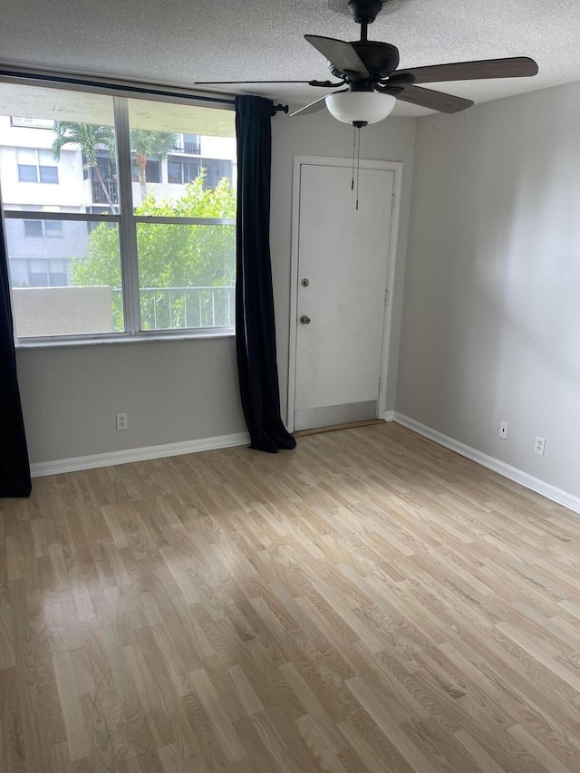 unfurnished room featuring a textured ceiling, ceiling fan, wood finished floors, and baseboards