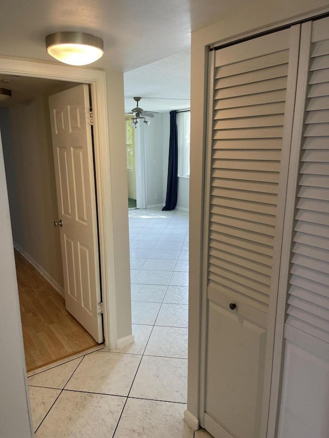 corridor with light tile patterned floors and baseboards