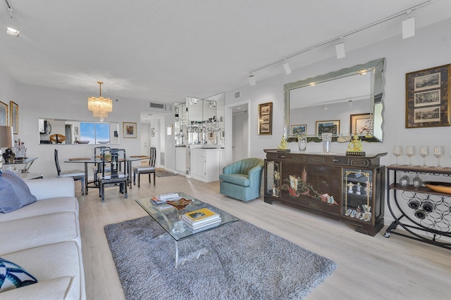 living area featuring visible vents, a notable chandelier, track lighting, and wood finished floors