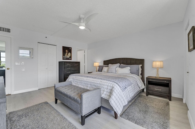 bedroom with light wood-style floors, a closet, visible vents, and a textured ceiling