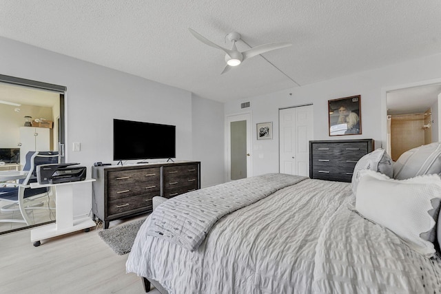 bedroom featuring a closet, visible vents, ceiling fan, a textured ceiling, and wood finished floors