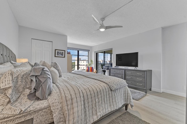 bedroom with a ceiling fan, baseboards, light wood-style flooring, and a textured ceiling