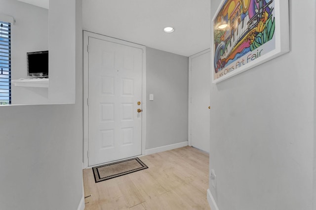 foyer entrance featuring baseboards, wood finished floors, and recessed lighting