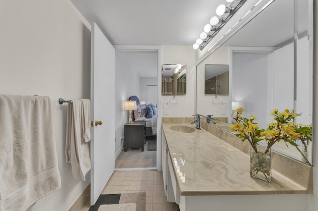 ensuite bathroom featuring baseboards, vanity, ensuite bath, and tile patterned floors