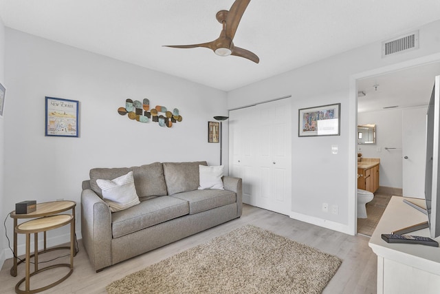 living room featuring light wood-style floors, visible vents, baseboards, and a ceiling fan