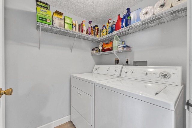 clothes washing area with a textured ceiling, laundry area, washing machine and clothes dryer, and baseboards