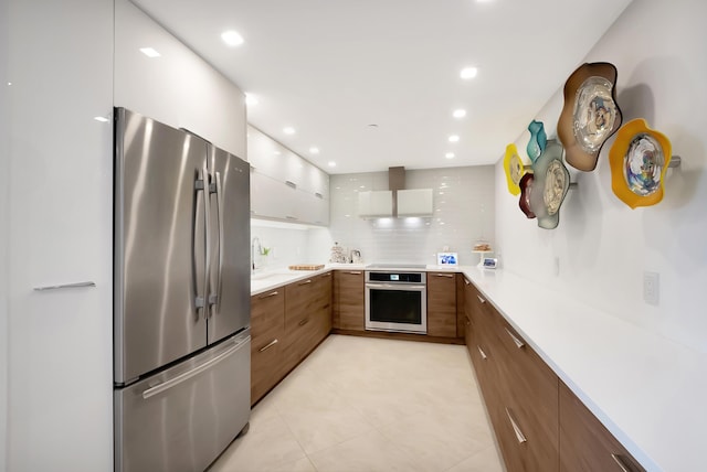 kitchen featuring stainless steel appliances, modern cabinets, brown cabinetry, and light countertops