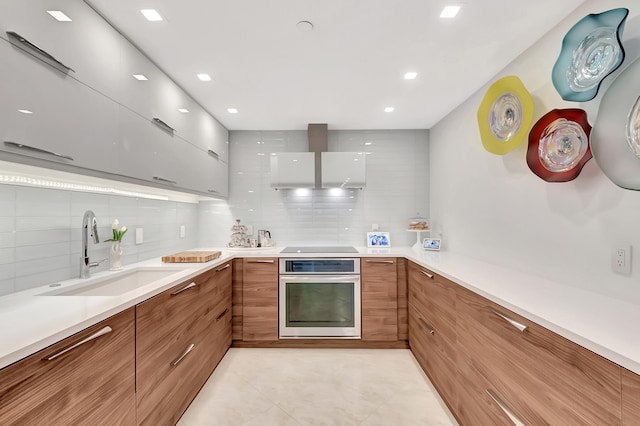 kitchen with oven, tasteful backsplash, modern cabinets, and a sink