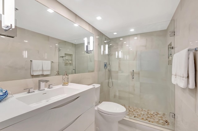 bathroom featuring toilet, tile walls, a stall shower, and vanity