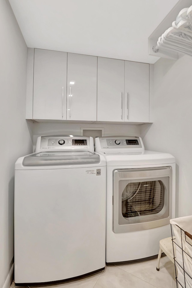 laundry area with washer and dryer, light tile patterned floors, and cabinet space