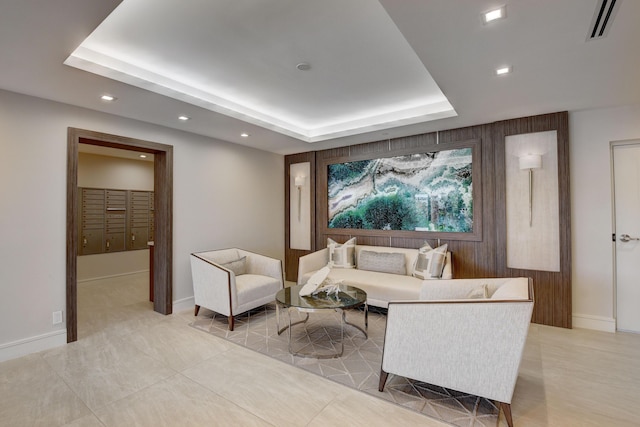 living area with wooden walls, visible vents, baseboards, a tray ceiling, and recessed lighting