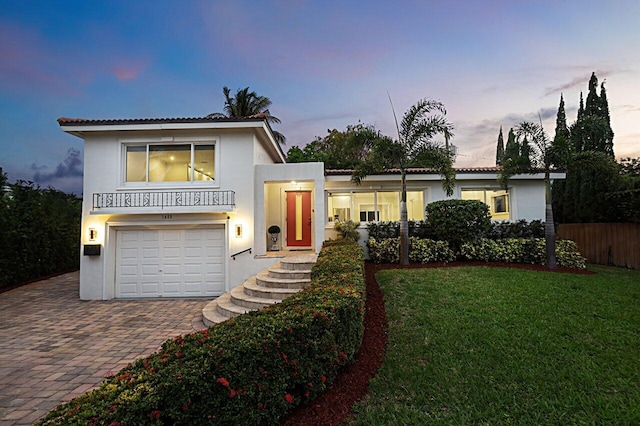 view of front of property featuring decorative driveway, stucco siding, a front yard, fence, and a garage