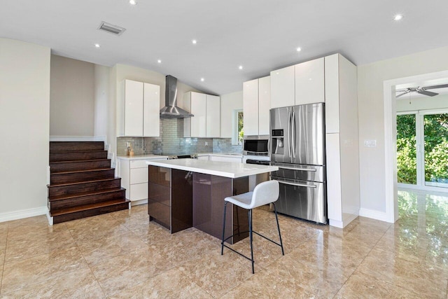 kitchen featuring appliances with stainless steel finishes, visible vents, wall chimney range hood, and modern cabinets