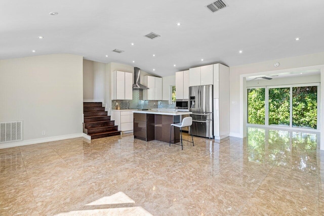 kitchen with appliances with stainless steel finishes, wall chimney range hood, and visible vents