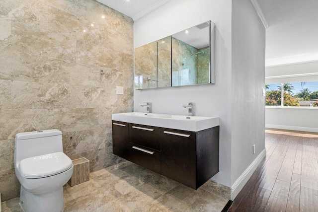 full bath featuring tile walls, toilet, wood finished floors, crown molding, and a sink