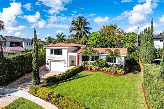 mediterranean / spanish-style house featuring a garage, a tiled roof, decorative driveway, and a front yard