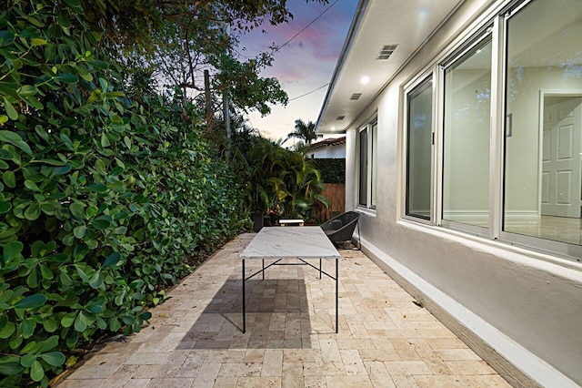 patio terrace at dusk with fence, visible vents, and outdoor dining space