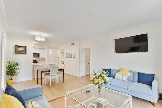 living room with ornamental molding, light wood-style floors, and baseboards