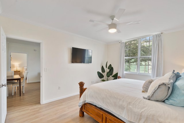 bedroom with ornamental molding, light wood-style floors, baseboards, and a ceiling fan