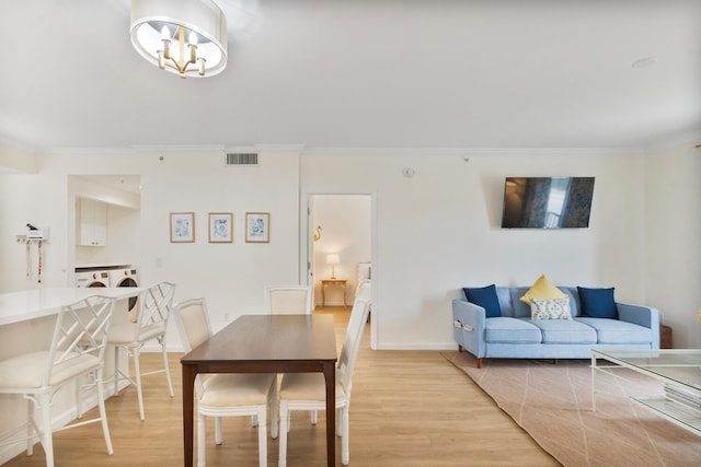 dining space featuring light wood-type flooring, visible vents, and crown molding