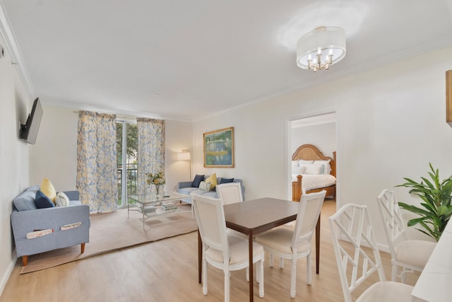 dining area featuring light wood finished floors, a notable chandelier, baseboards, and crown molding