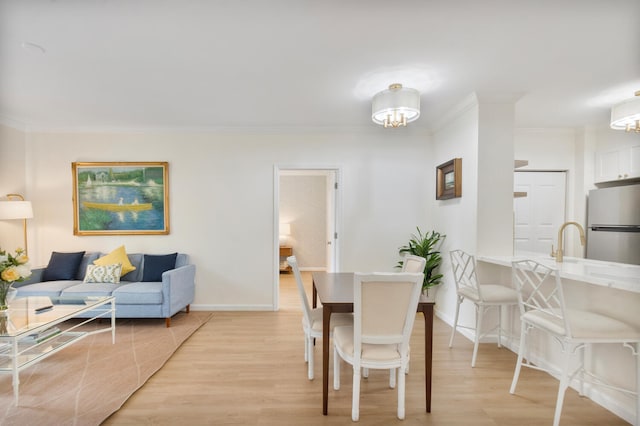 dining space featuring ornamental molding, baseboards, and light wood finished floors