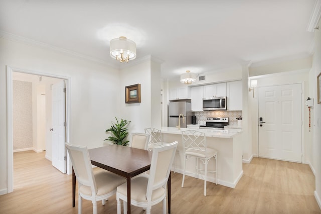 dining room with visible vents, baseboards, ornamental molding, an inviting chandelier, and light wood-style floors