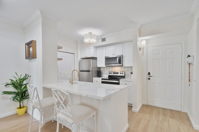 kitchen with appliances with stainless steel finishes, visible vents, a sink, and light wood finished floors